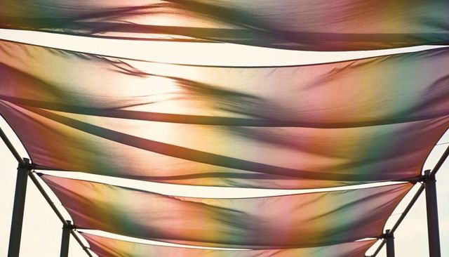 Colorful translucent shade sails stretching across metal frames creating gradient canopy