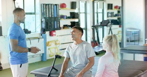 Physical therapist consulting patient after leg injury, team assessing mobility in rehab gym