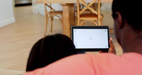 Father and Daughter Using Tablets Together in Cozy Living Room