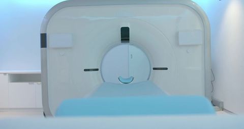 High-tech mri scanner filling clinical suite with patient table, blue cushion and lighting