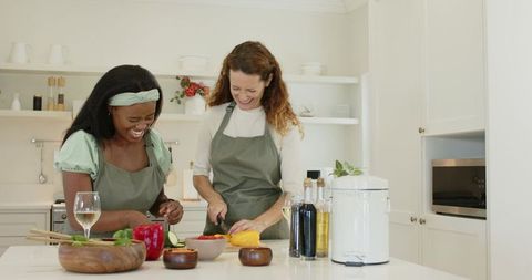 Diverse friends cooking with fresh ingredients in modern kitchen