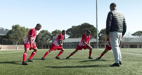 Soccer Team Warm-Up with Coach Under Sunny Sky