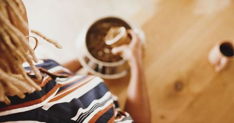 Senior woman preparing pet food at wooden table in cozy home