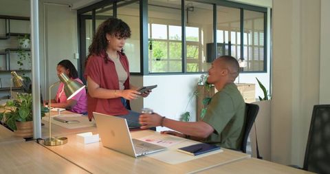 African american coworkers collaborating at bright coworking desk with laptop and tablet