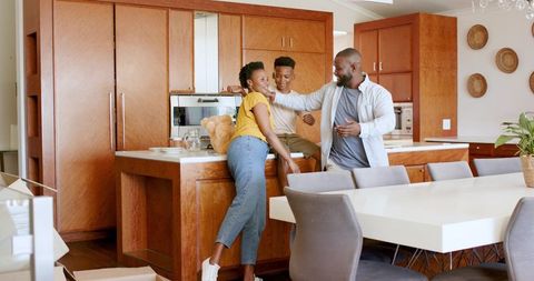 African american family laughing and bonding around kitchen island in modern open-plan home