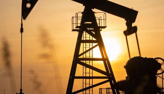 Pumpjack silhouette at sunset over plains, backlit oilfield machinery and energy landscape