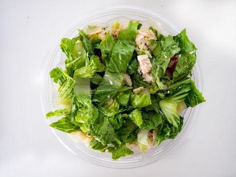Featuring fresh chicken caesar salad in clear plastic bowl overhead view for healthy lunch