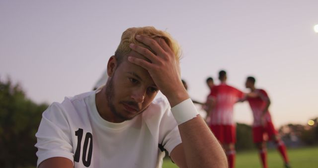 Disappointed Soccer Player Reacting to Loss While Teammates Discuss - Download Free Stock Images Pikwizard.com