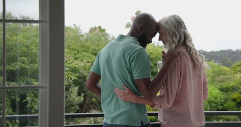 Couple Embracing on Balcony Enjoying Nature View With Wine
