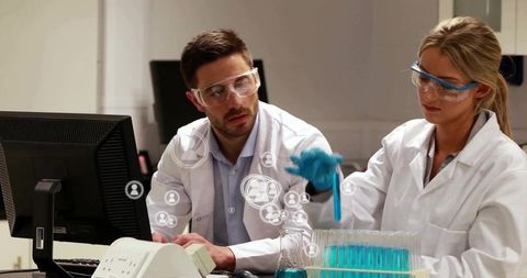 Two Scientists Pipetting Blue Liquid at Laboratory Bench Conducting Biotech Experiment