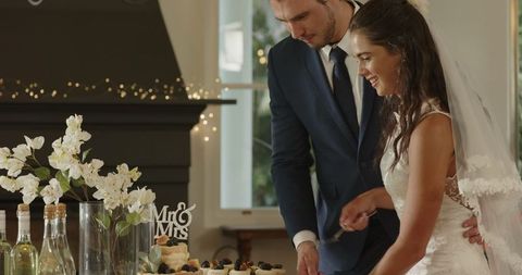 Bride and Groom Joyfully Cutting Wedding Cake in Elegant Ceremony