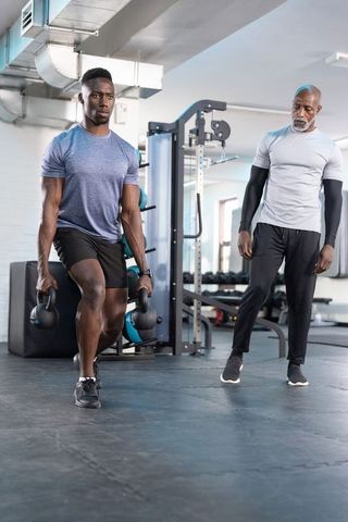 Kettlebell lunging with coach using tablet ar to track athlete form and improve strength