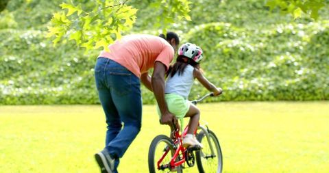 Father Helping Daughter Ride Bicycle Outdoors
