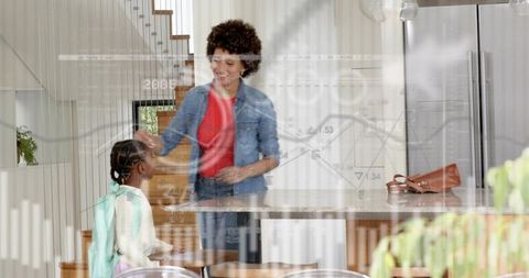 Smiling woman greeting schoolgirl with mint backpack in modern kitchen morning routine