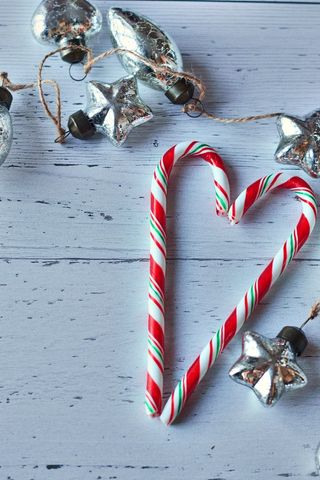 Festive candy cane and silver ornaments on white wooden surface
