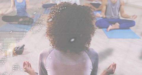 Curly-haired woman practicing meditation in group yoga class with soft dotted overlay