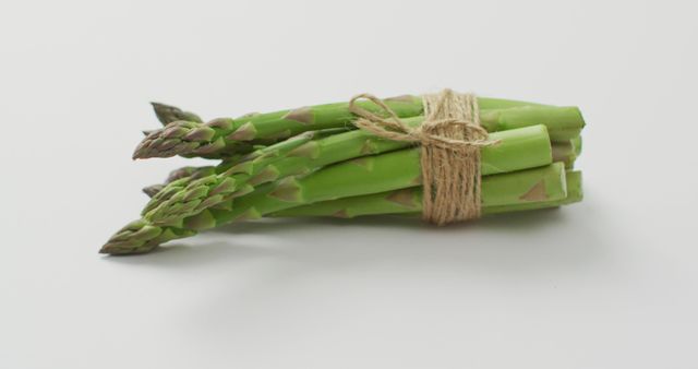 Image of close up of bundle of fresh asparagus over white background. fusion food, fresh vegetables and healthy eating concept.