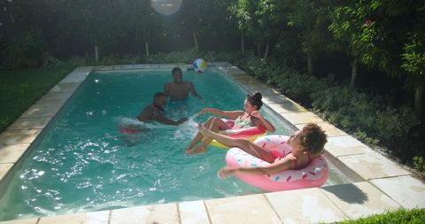 Friends splashing and enjoying relaxing day in backyard pool