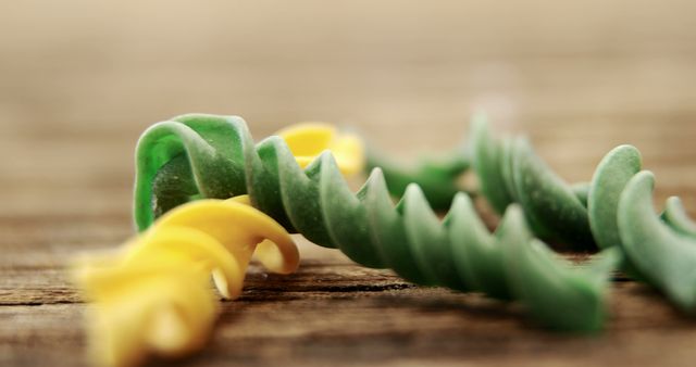 Close-up of raw colorful spiral pasta on wooden table - Download Free Stock Images Pikwizard.com