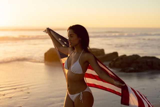 Woman in bikini holding an American flag on the beach - Download Free Stock Photos Pikwizard.com