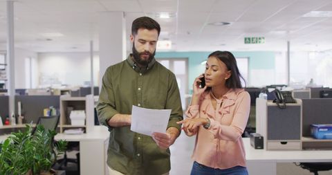 Business colleagues discussing work while walking in modern office