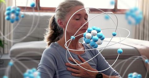 Senior woman practicing mindful breathing viewing augmented molecular wellness technology