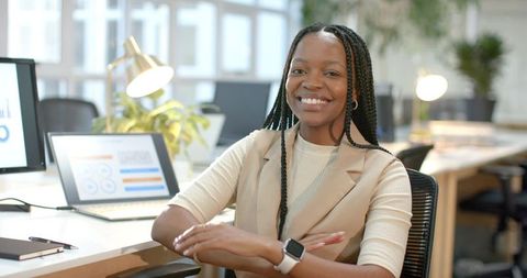Confident African American Businesswoman Smiling at Desk in Modern Office with Laptop