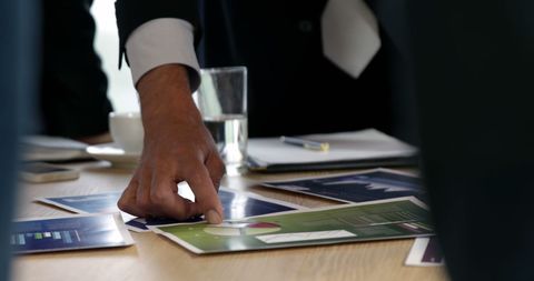 Businessman's Hand Pointing at Charts During Strategy Meeting