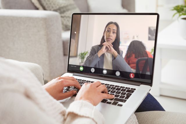African american businesswoman with hands clasped during video call with caucasian female colleague. unaltered, work from home, business, wireless technology, working, teamwork and office concept.