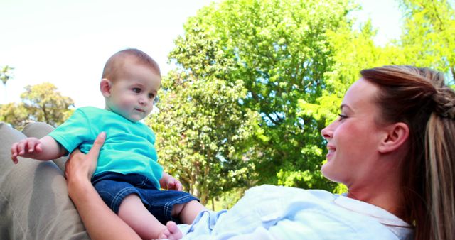 Smiling Mother Holding Baby in Park on Sunny Day - Download Free Stock Images Pikwizard.com