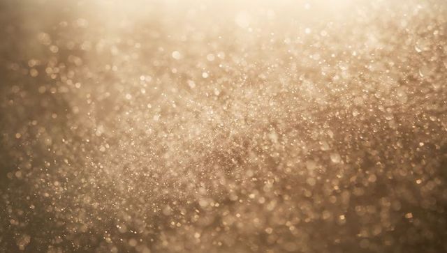 Shimmering golden bokeh sparkle with warm glittering particles and soft glow