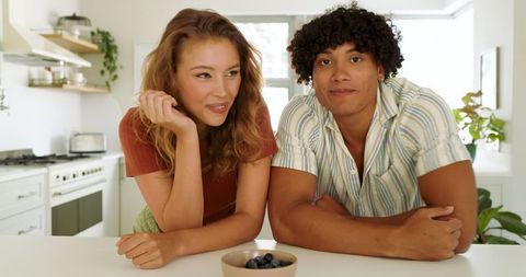 Happy Couple Sampling Fresh Blueberries in Modern Kitchen