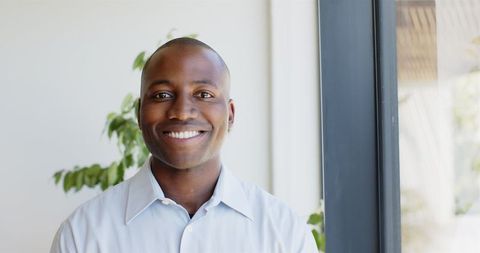 Smiling Man Standing by Window in Clean Bright Space