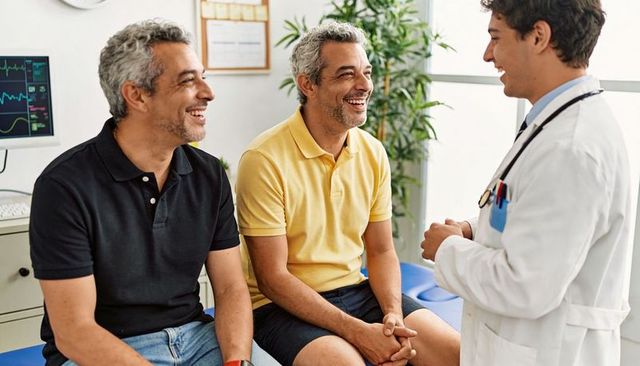 Smiling men consulting doctor on blue exam bench in bright clinic, friendly medical visit