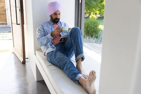 Man relaxing and reading magazine by doorway
