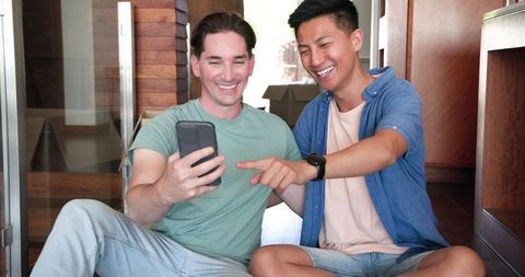 Happy diverse men enjoying video call in new home
