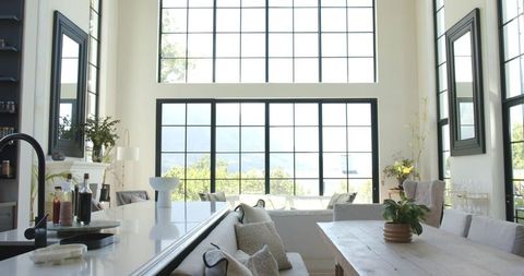 Sunlit modern open-plan living dining with black grid windows and kitchen island