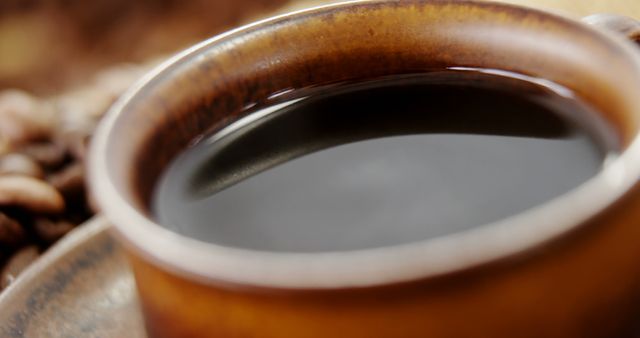 A close-up view of a steaming cup of coffee in a ceramic mug, with coffee beans in the background, with copy space. Coffee enthusiasts often appreciate such images that evoke the aroma and warmth of freshly brewed coffee.