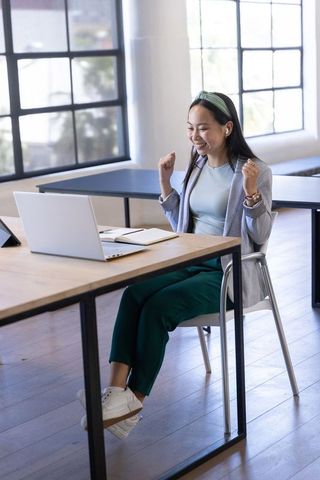 Joyful asian businesswoman celebrating success in modern office