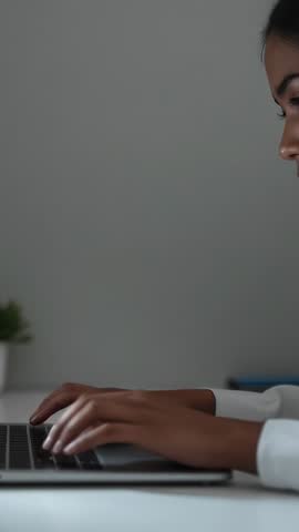 Woman typing on laptop, reviewing notes and focusing in minimalist workspace vertical clip