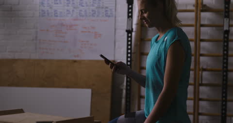 Athletic Woman Smiling While Using Smartphone in Gym