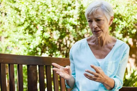 Senior Woman Engaged in Conversation Outdoor in Sunny Garden