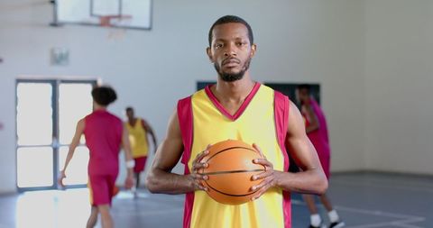 Confident Basketball Player Holding Ball in Gym