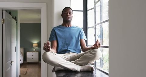 Man meditating peacefully by window embracing serenity