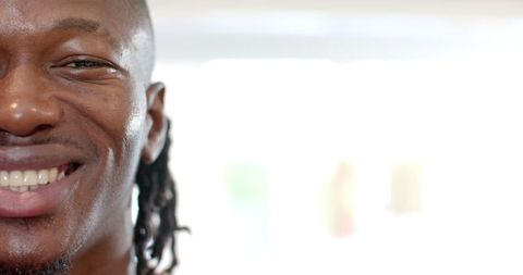 Partial profile of smiling man with dreadlocks on white background