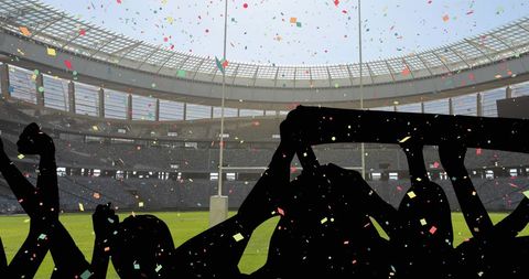 Silhouette of excited fans with confetti in stadium