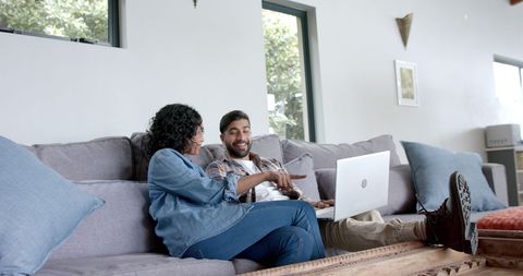 Happy Couple Enjoying Laptop on Cozy Sofa at Home