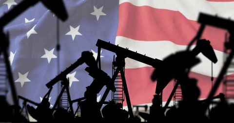 Oil pump jacks silhouetted against waving american flag conveying energy industry power