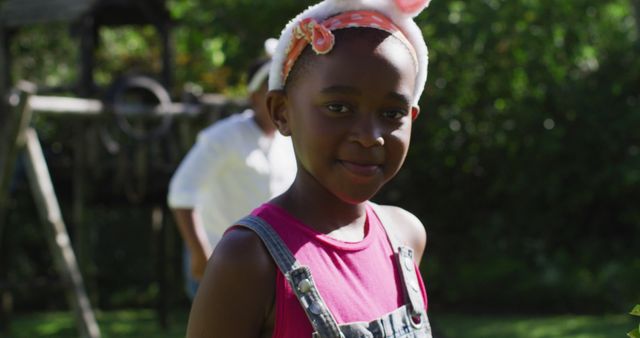 African american girl wearing easter bunny ears doing easter egg hunt in garden with brother. family spending easter time together staying at home in isolation during quarantine lockdown.