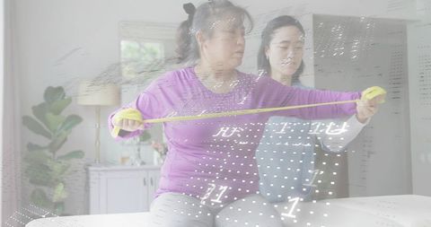 Home therapist assisting woman with resistance band exercise during mobility assessment